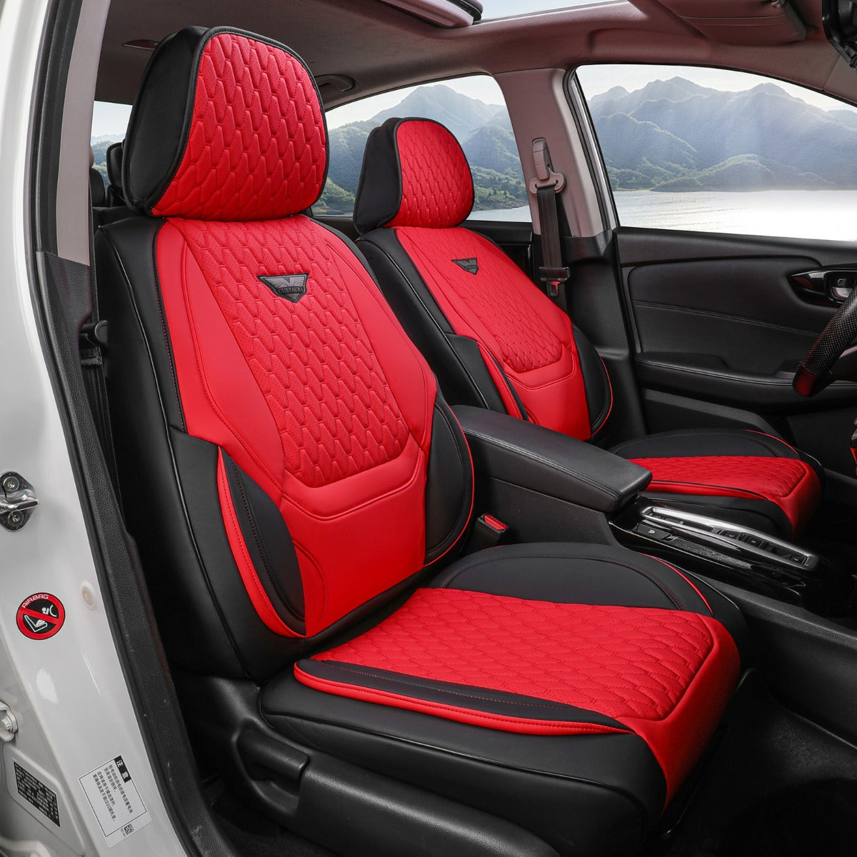 Red and black car seat covers inside a vehicle with a mountainous landscape outside.