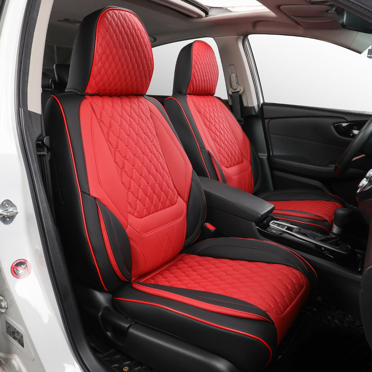 Red and black car seat covers installed on the front seats of a vehicle, shown from the open driver-side door. The covers have a quilted diamond pattern and are fitted over the seats inside a black car interior.