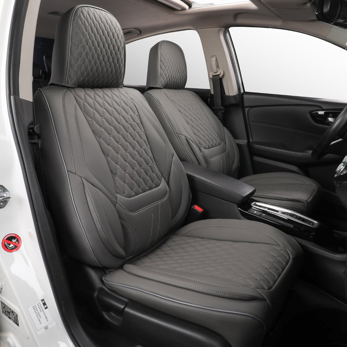 Gray quilted leather car seat covers installed on the front seats of a vehicle, shown from an open door view.