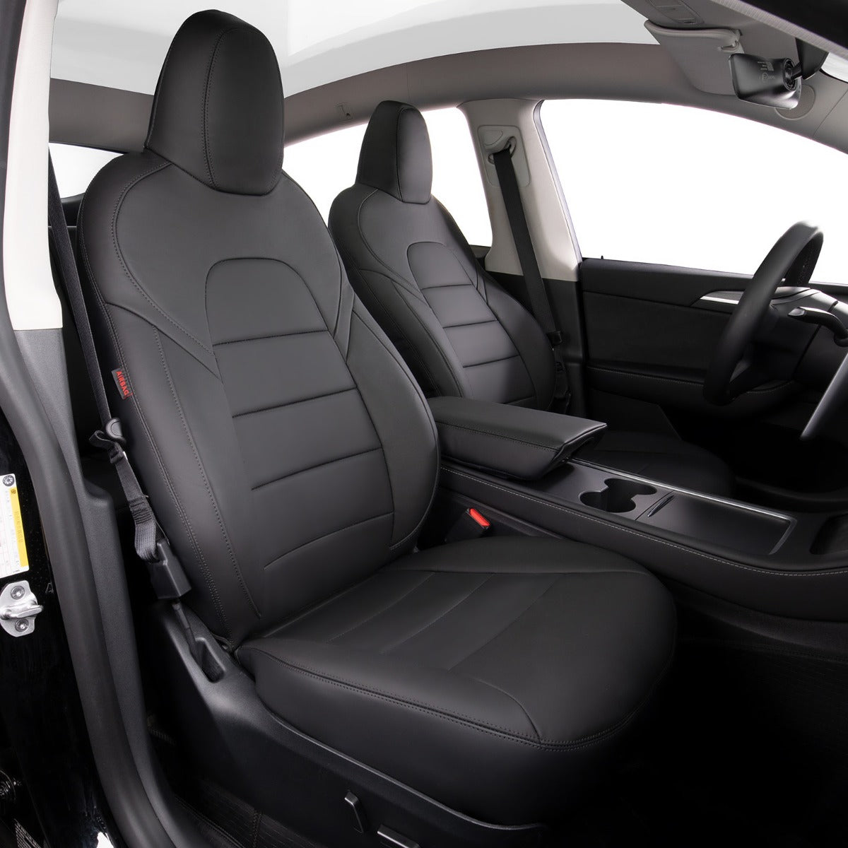Black leather car seat covers installed on the front seats of a vehicle interior, shown from the open driver's side door.