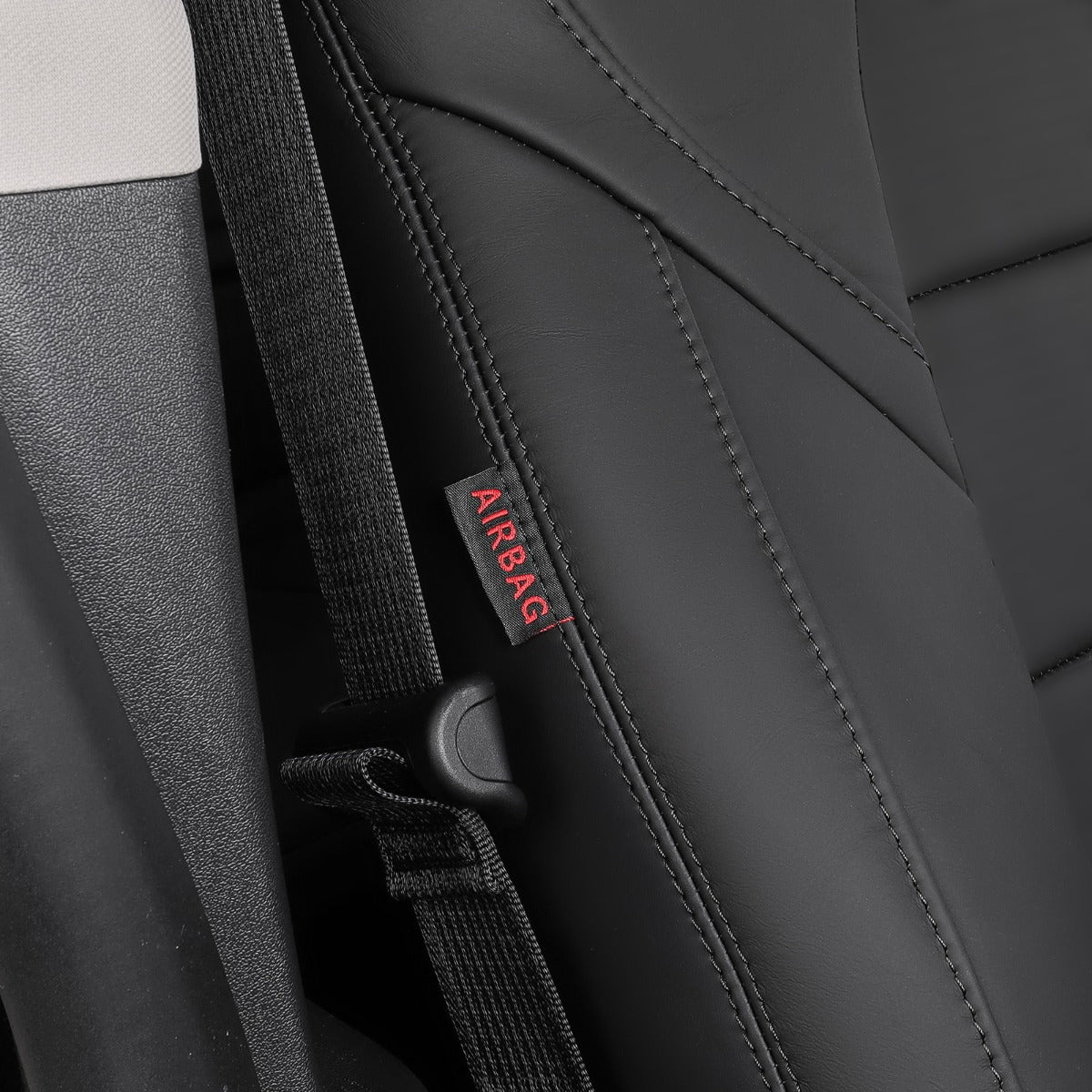 Close-up of a black car seat with a black seatbelt and a small fabric tag reading AIRBAG in red text.