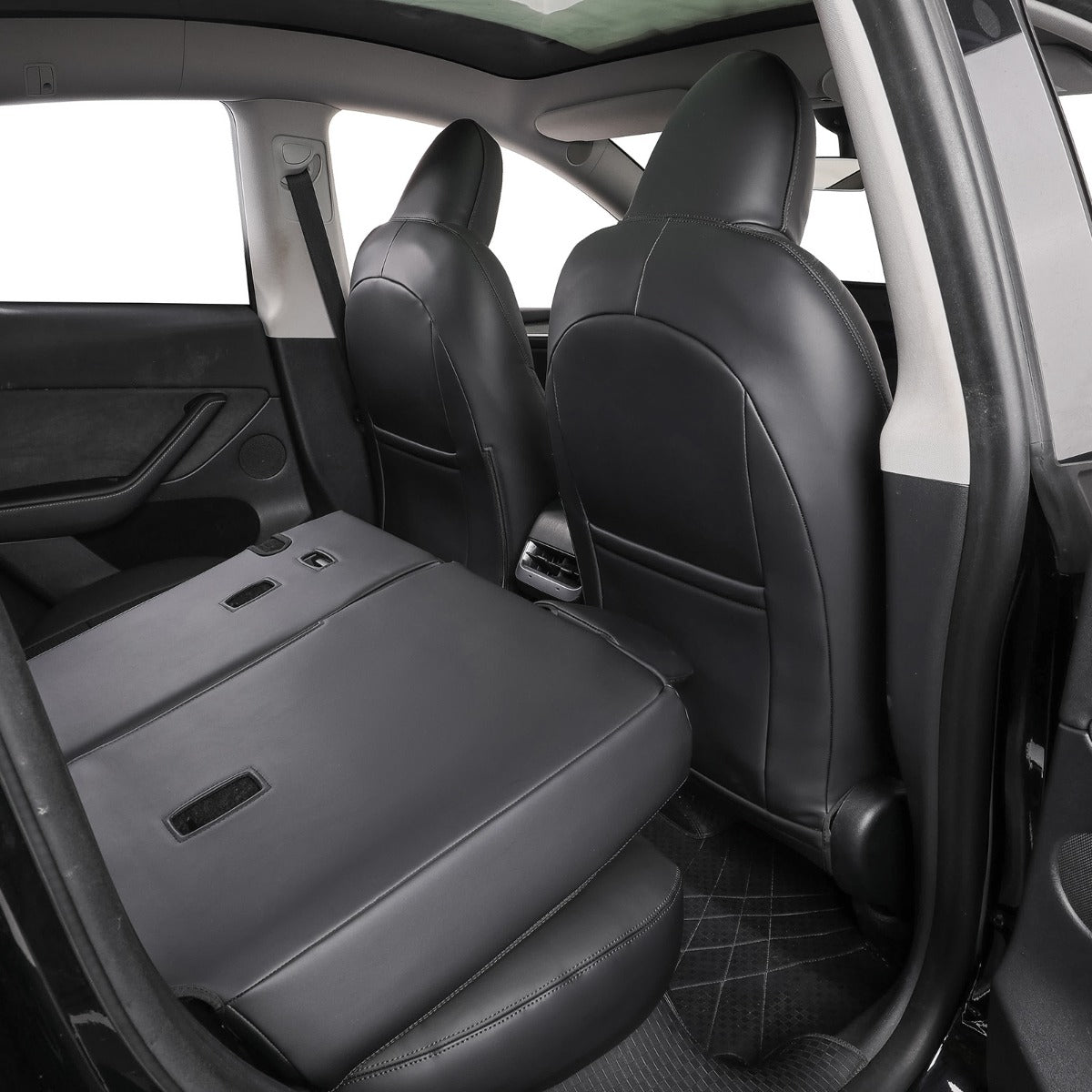 Black leather car interior showing the folded-down rear seat and the adjacent front seats, photographed from an open rear door.