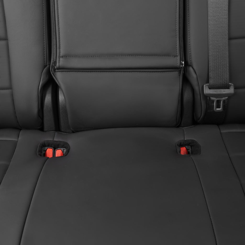 Close-up of a black leather car seat with an integrated headrest, side seatbelt buckle, and red release buttons on the seat base.