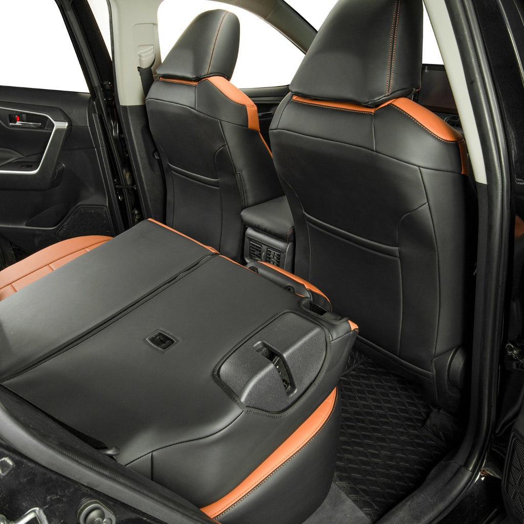 Rear car seats in a vehicle interior, upholstered in black leather with bright Brown contrast stitching and trim. The third-row seat is folded down, showing the floor mat and center console area.