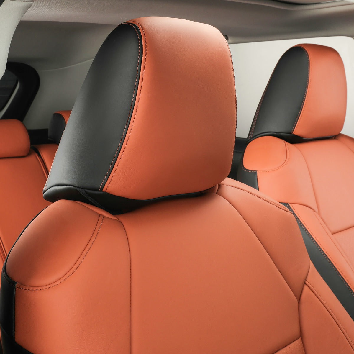 Brown and black leather car seat covers installed on the front seats of a vehicle interior.