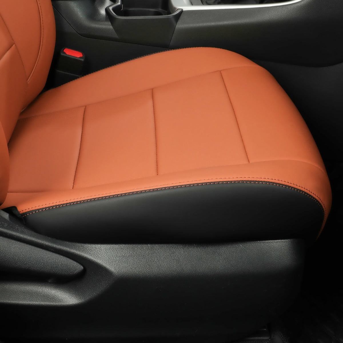 A close-up of a car seat cover installed on a vehicle's front seat, featuring a two-tone design with textured Brown -brown upper sections and black lower sections.