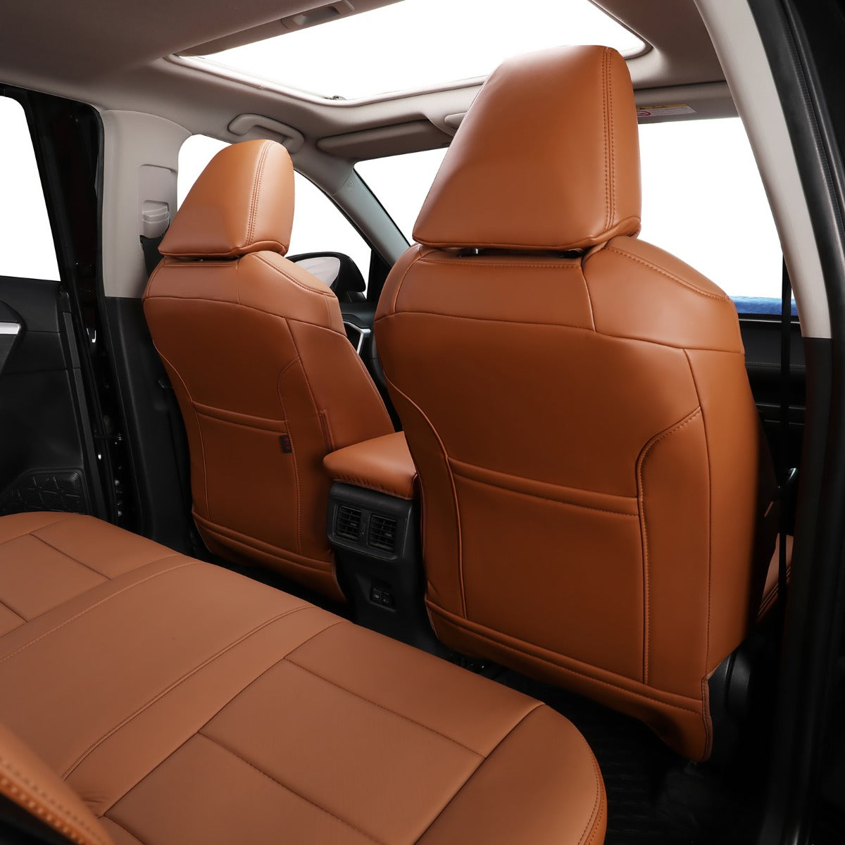 Brown leather car seat covers installed on the front and rear seats of a vehicle interior, shown from an open side door with bright windows.