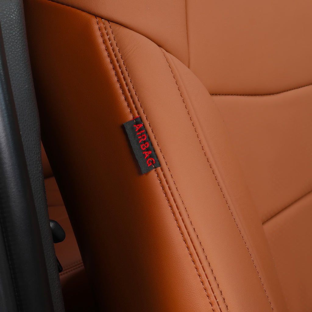 Close-up of a tan leather car seat with visible stitching and a small black fabric tag reading AIRBAG in red text.