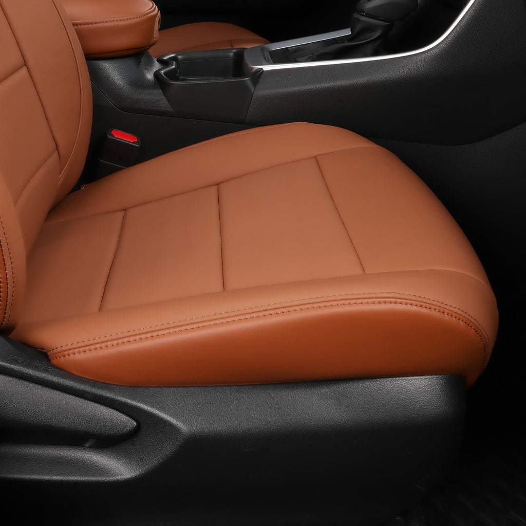 A close-up of a car's front passenger seat covered in a tan-brown leather or faux-leather seat cover, with the black car interior visible around it.