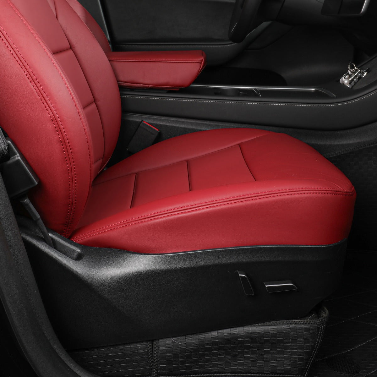 A pair of burgundy car seat covers installed on the front passenger and driver seats inside a black car interior.