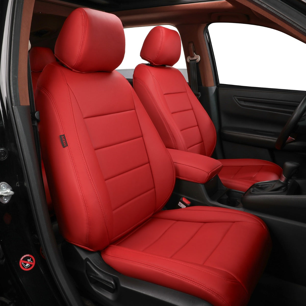 Red car seat covers installed on the front seats of a vehicle interior, shown from the open driver-side door with black seats and car interior visible around them.
