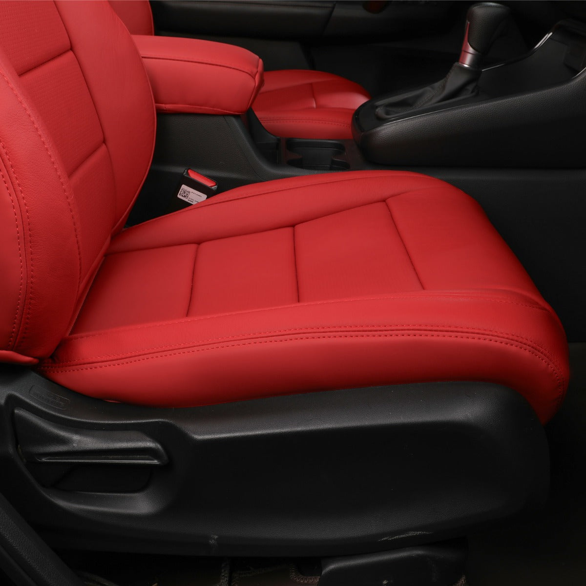 Red car seat covers installed on the front passenger seat and center console armrest, shown inside a black car interior.
