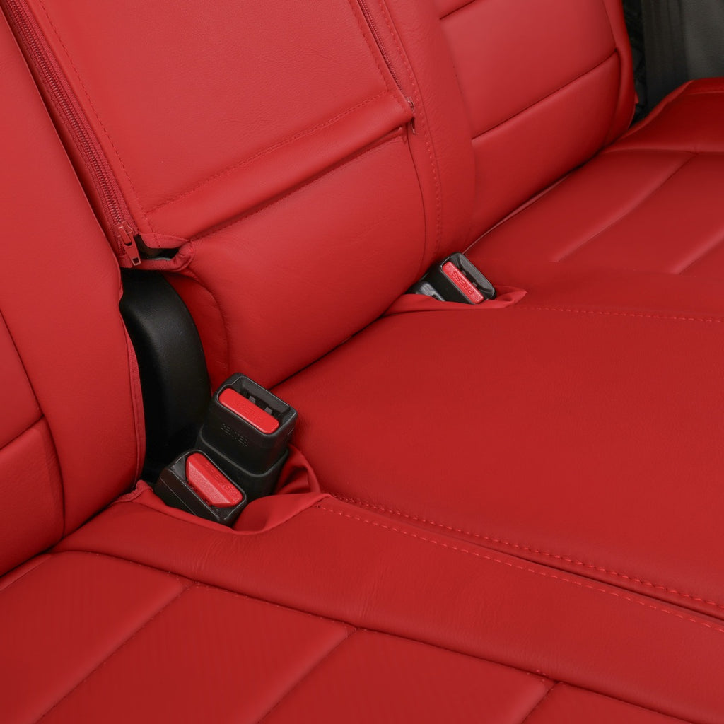 Close-up of a red leather car seat with black and red seat belt buckles visible at the side and center.