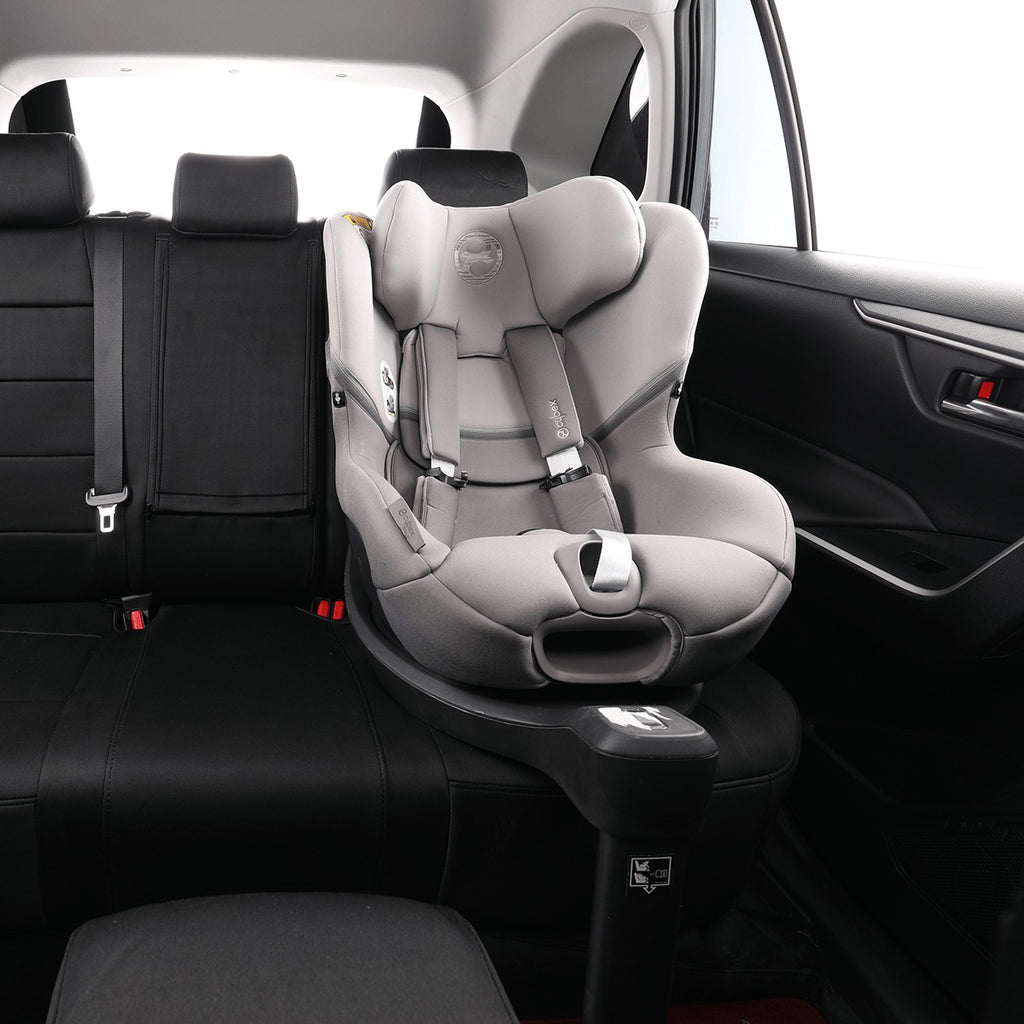 A light gray and black infant car seat with a matching base installed in the rear seat of a black car interior.