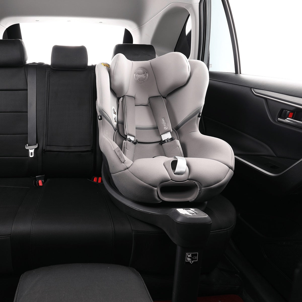 A light gray and black infant car seat with a matching base installed in the rear seat of a black car interior.