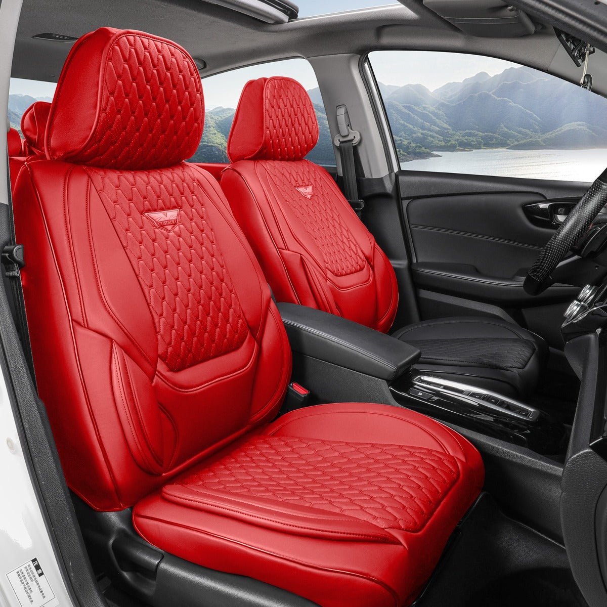Red car seat covers with quilted diamond stitching installed on the front seats of a black car interior, with a scenic mountain lake view visible through the windows.
