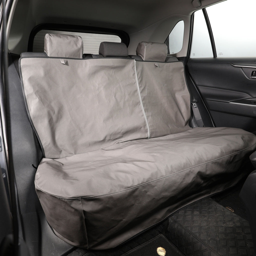 A gray car seat cover installed on a three-seat rear bench inside a vehicle, shown from the open rear door.
