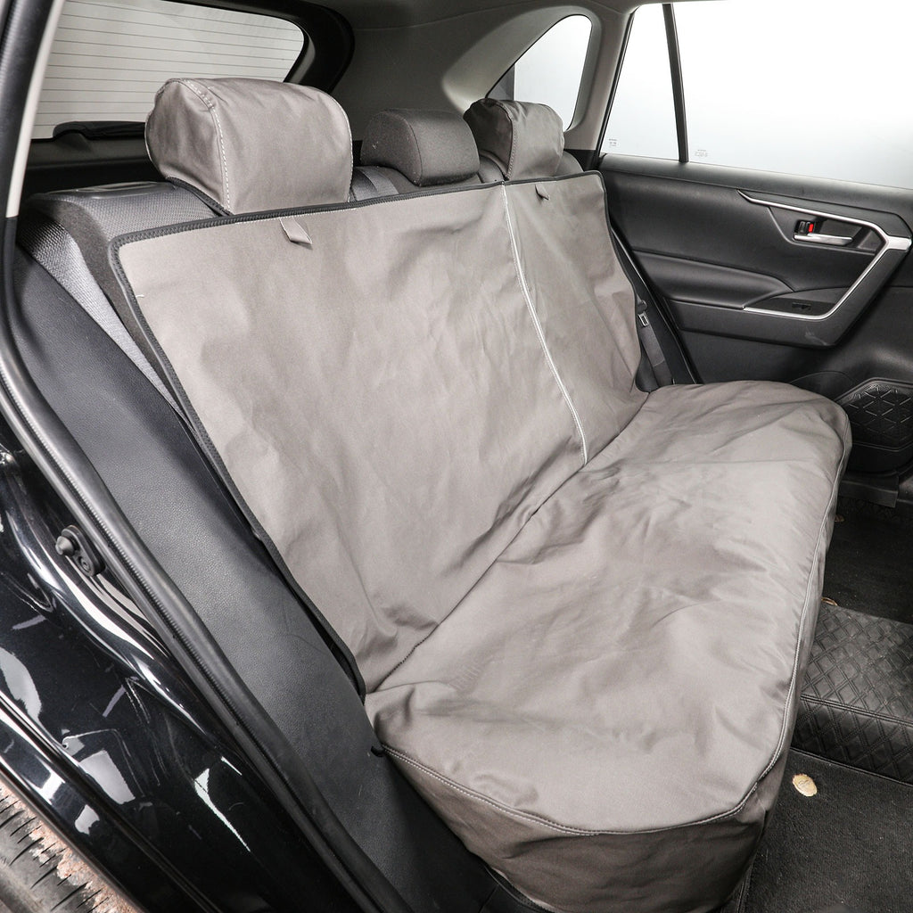 A gray car seat cover installed on the back seat of a vehicle, shown from the rear door area with the seat headrests and car interior visible.