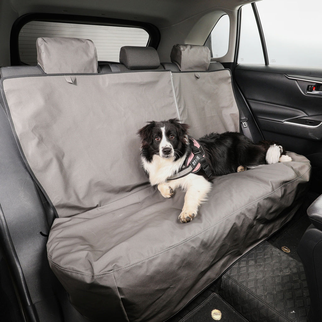 Dog lying on a gray car seat cover in a vehicle