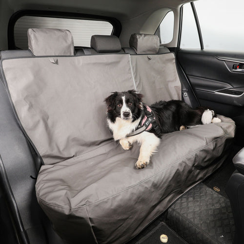 Dog lying on a gray car seat cover in a vehicle