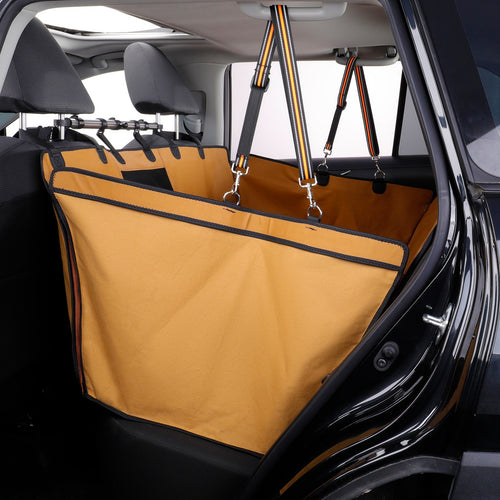 A tan dog car seat cover with black trim and adjustable straps hanging over the rear seats of a black vehicle.