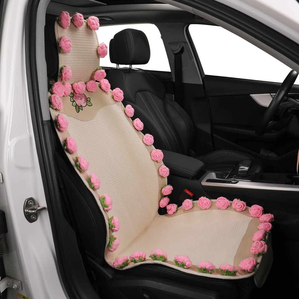 A beige car seat cover on the front passenger seat of a black car, decorated with pink 3D roses and green leaves along the edges.